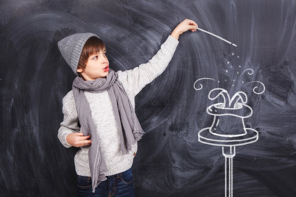 A child drawing an imaginary magic trick on a blackboard
