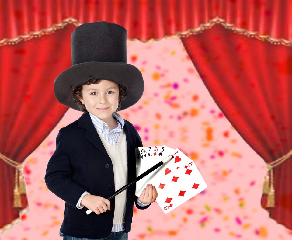 A child magician presenting colourful playing cards on stage