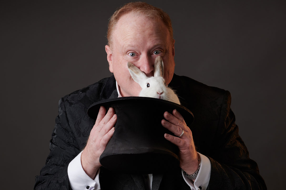 Jimmy Marvel holding a rabbit in a top hat, with the rabbit’s ears framing his face